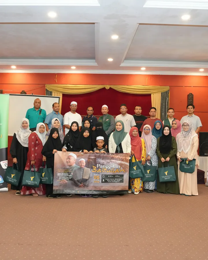 Rombongan besar jemaah Travelty dengan beg hijau dan banner